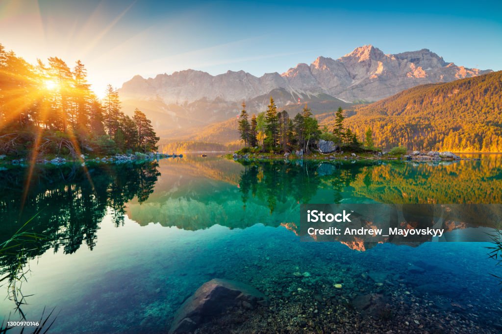 Impressive summer sunrise on Eibsee lake with Zugspitze mountain range. Sunny outdoor scene in German Alps, Bavaria, Germany, Europe. Beauty of nature concept background. Mountain Stock Photo