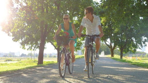 istock LENS FLARE: Couple enjoys an active date by riding bicycles down sunlit avenue 1300971815