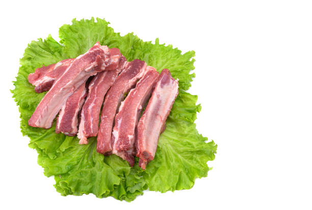 Raw pork ribs on a lettuce leaf are isolated on a white background.Selective focus.