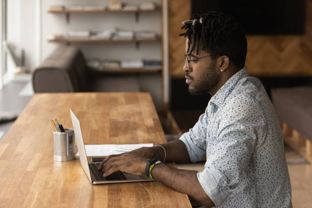 istock Focused black young man typing on laptop looking at screen 1300971876