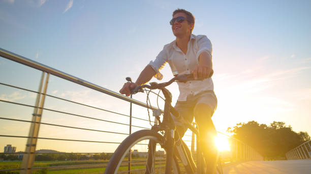 istock LENS FLARE: Carefree man enjoys a sunny summer evening by riding a bicycle. 1300972505