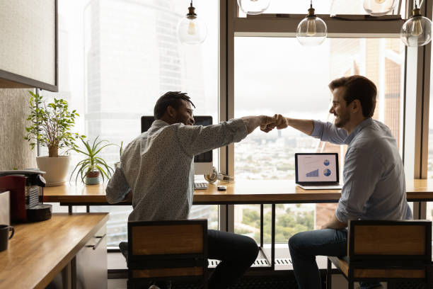 due lavoratori membri del team internazionale condividono il successo aiutarsi a vicenda - gesturing two people business talking foto e immagini stock