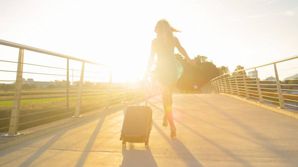 レンズフレア:観光客の女の子は日没時に空港に歩いている間に踊り回ります。 - shoe leaving women summer ストックフォトと画像