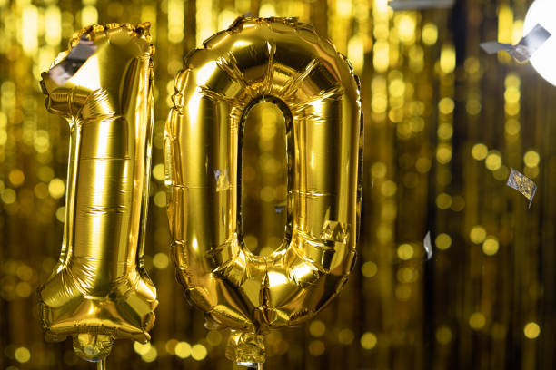 Gold foil number 10 ten festive balloon on a yellow background. The concept of birthday, anniversary, date. Gold foil number 10 ten festive balloon on a yellow background. The concept of birthday, anniversary, 10 balloon stock pictures, royalty-free photos & images