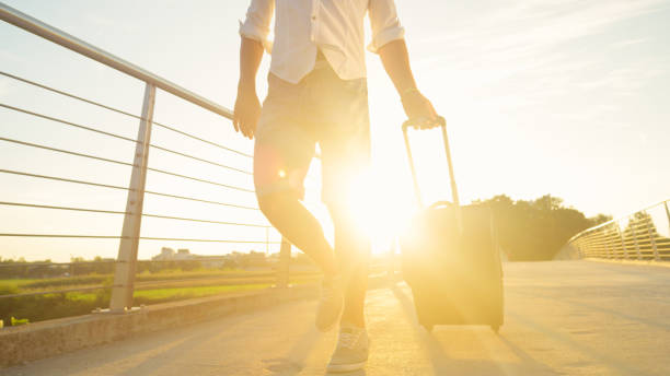 istock LOW ANGLE: Unrecognizable man walks across a bridge with his baggage at sunrise. 1300973036