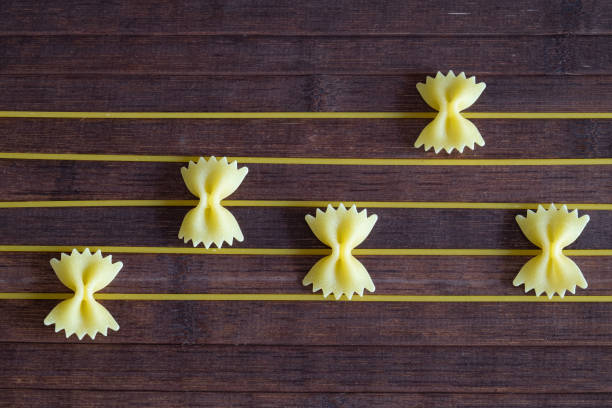 istock Creative composition of a sheet of a musical score, the notes are created with raw butterfly-shaped paste resting on a wooden background and the stripes with spaghetti. 1300973257