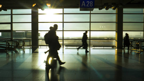 istock SILHOUETTE: Unrecognizable tourists hurry down an airport terminal at sunrise. 1300975170
