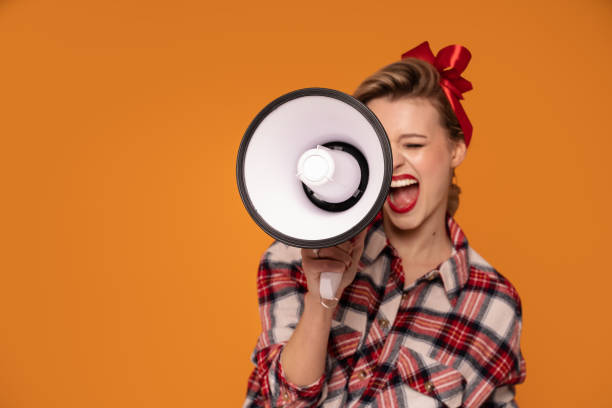 istock Smiling happy pinup woman screaming through megaphone. 1300976240