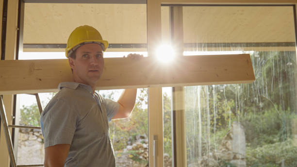 istock CLOSE UP: Builder walks across a sunlit room with a wooden panel on his shoulder 1300976356