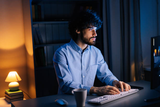 istock Exhausted freelancer watching on monitor, working typing on keyboard and drinking hot coffee. 1300976698