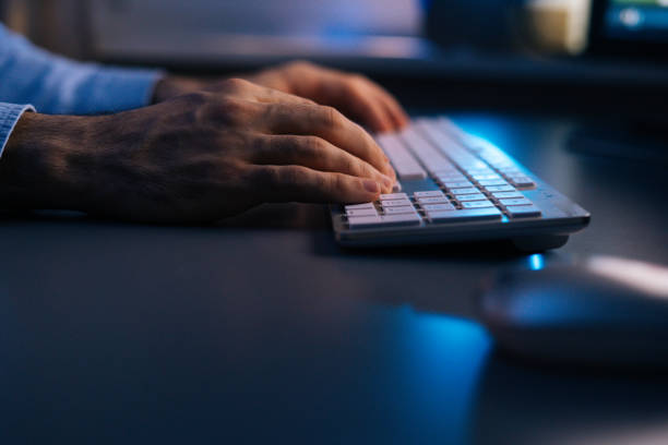 istock Side view of unrecognizable man typing online message using wireless keyboard at late night. 1300976839