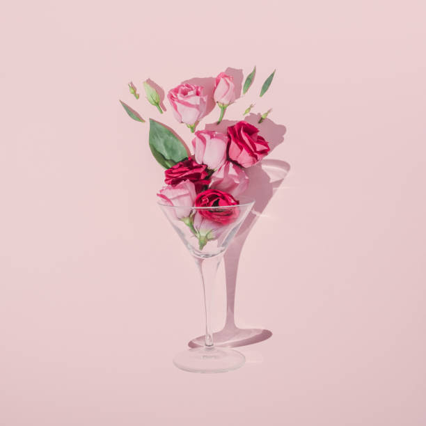 romantyczna kompozycja walentynkowa wykonana ze szkła koktajlowego, zielonych liści i różowych róż na pastelowym tle. minimalny płaski lay. - flower drink zdjęcia i obrazy z banku zdjęć