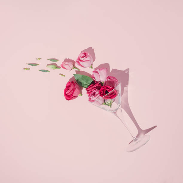 zabawa układ strony stworzony ze szkła koktajlowego, zielone liście i różowe róże na pastelowym tle. kreatywne wiosenne płaskie układanie. - flower drink zdjęcia i obrazy z banku zdjęć