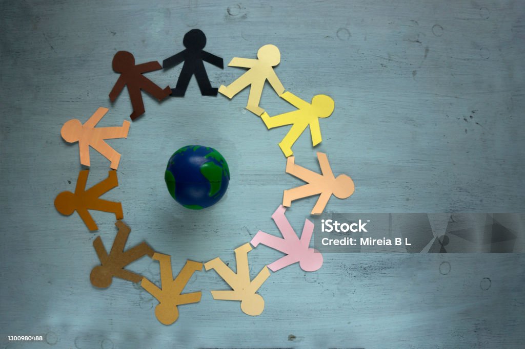 Humanity races protecting our planet Earth together as a society Paper dummys in different human races colors joined together to save the planet Human Rights Stock Photo