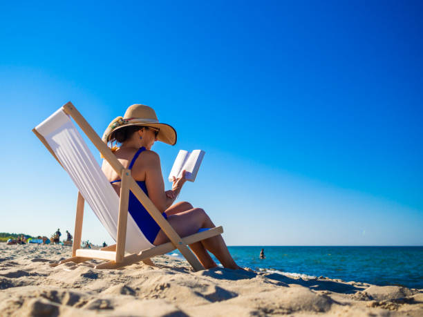 istock Woman relaxing on beach readin book 1300982439