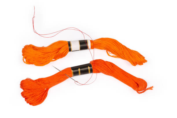 istock Skeins of orange stranded embroidery floss and hand sewing needle 1300982565