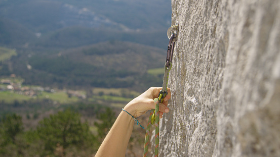 A bearded man climbs a mountain using a special rope and climbing equipment