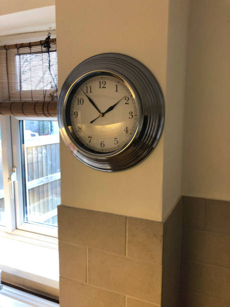 istock Image of chrome kitchen clock in empty rental property, magnolia painted tiled walls, window over looking domestic garden 1300984302