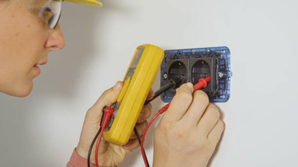 CLOSE UP: Young female electrician checks a socket with a new multimeter. CLOSE UP: Experienced female electrician checks a newly installed socket with a new multimeter. Young Caucasian woman wearing a yellow hard hat inspects the electricity running through the socket. electrolux range repair stock pictures, royalty-free photos & images