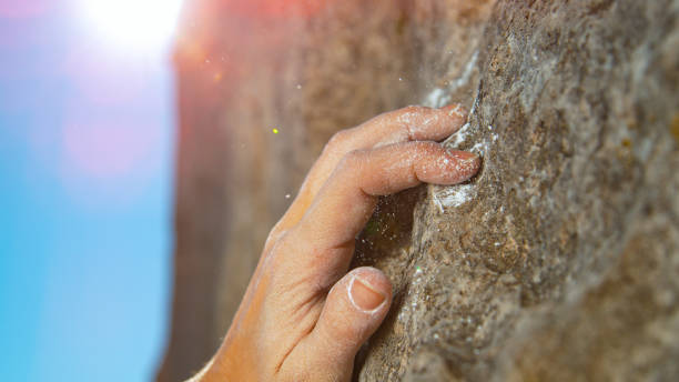 istock MACRO, LENS FLARE: Woman grabs a crimp hold while scaling a challenging cliff. 1300984684