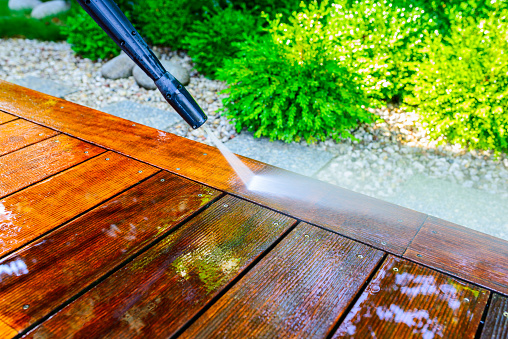 limpieza de la terraza con una lavadora a presión - limpiador de alta presión en la superficie de madera de la terraza - muy poca profundidad de campo - nitidez en el tablero de la terraza bajo un arroyo de agua photo