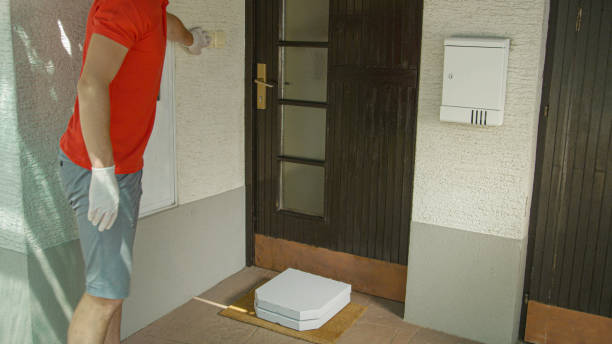 istock CLOSE UP: Delivery guy rings doorbell after leaving two pizza boxes on doormat. 1300986335