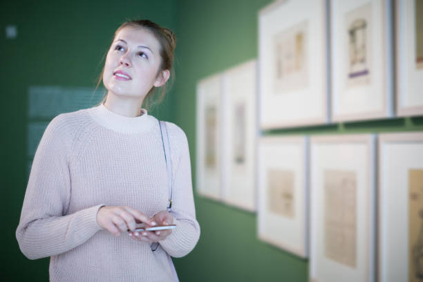 istock Positive female visitor using mobile in the museum 1300987345