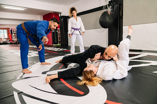 group of four judo martial arts partners and an instructor practicing new techniques on a gym mat