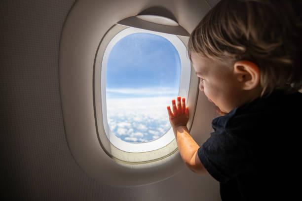 istock cute toddler points his finger at the sky through the window. first flight concept, traveling with children. 1300990028