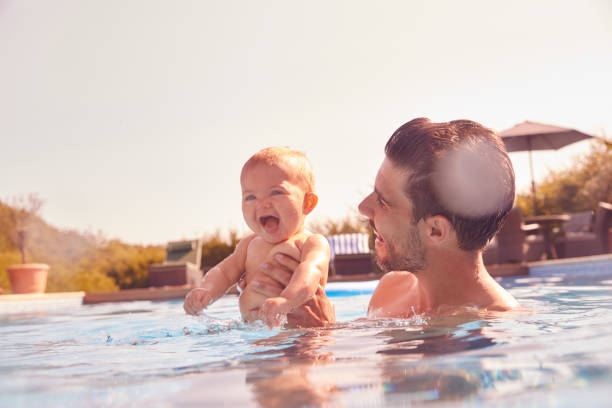 vater mit baby-tochter spaß im sommerurlaub spritzen im freibad - sports venue clothing outdoors front view stock-fotos und bilder