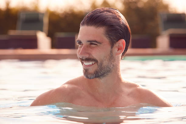 uomo sorridente rilassante durante le vacanze estive in piscina all'aperto - splashing color image front view head and shoulders foto e immagini stock