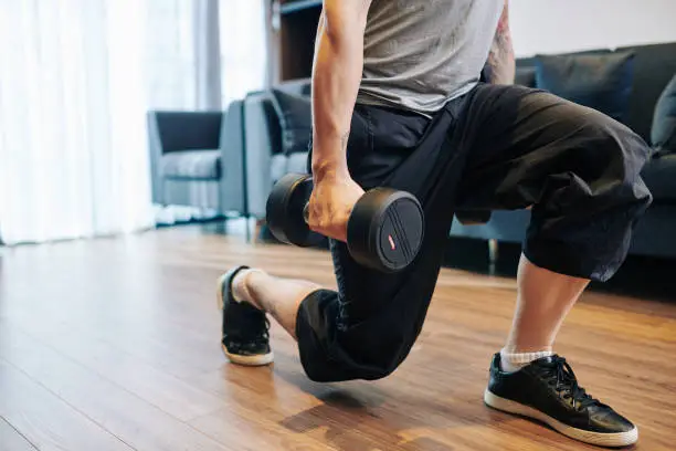 Photo of Man doing lunges with dumbbells