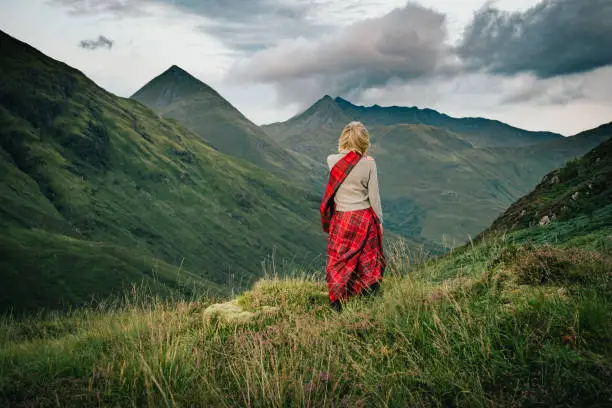 Woman in scottish kilt above Glen Shiel, in the Highlands of Scotland. View is west towards The Saddle and Faochag.