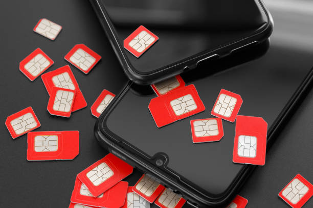 Lots of SIM cards and two cell phones Two cell phones and a lot of SIM cards. The concept of fraud, deception, mass dialing. sim cards stock pictures, royalty-free photos & images