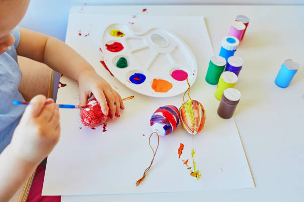 istock Adorable little girl painting eggs for Easter 1300993554