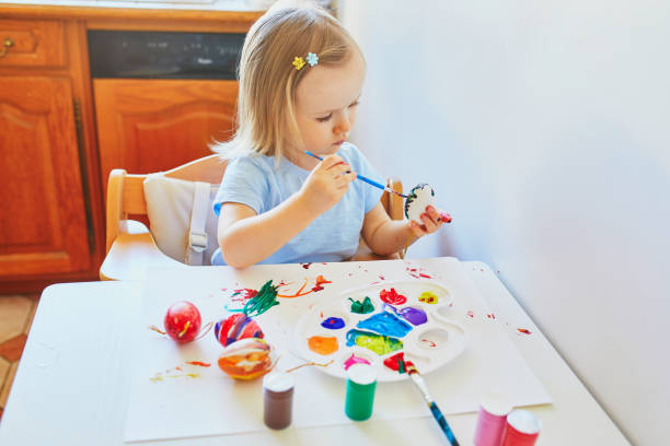 istock Adorable little girl painting eggs for Easter 1300993708