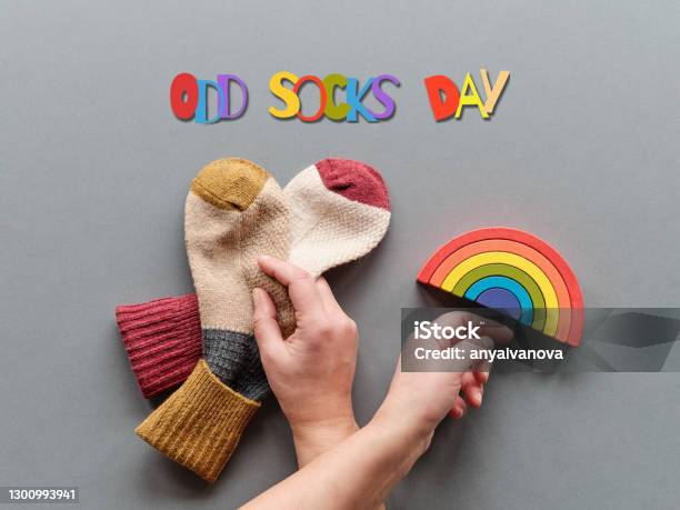Odd Socks Day Hand Hold Pair Of Mismatched Socks Wooden Rainbow Toy Figures Social Initiative Against Bullying In School Or Workplace Design For Antibullying Campaign Promotion Poster Stock Photo - Download Image Now