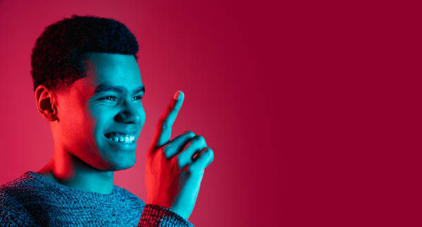 African-american man's portrait isolated on red studio background in multicolored neon light