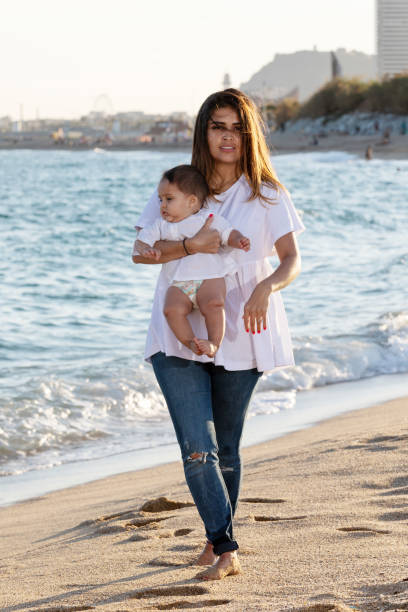 istock Mom holding her son toward the blue sky while walking on the beach 1300995420
