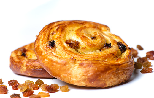 Freshly baked delicious sweet bun with raisins isolated on white background