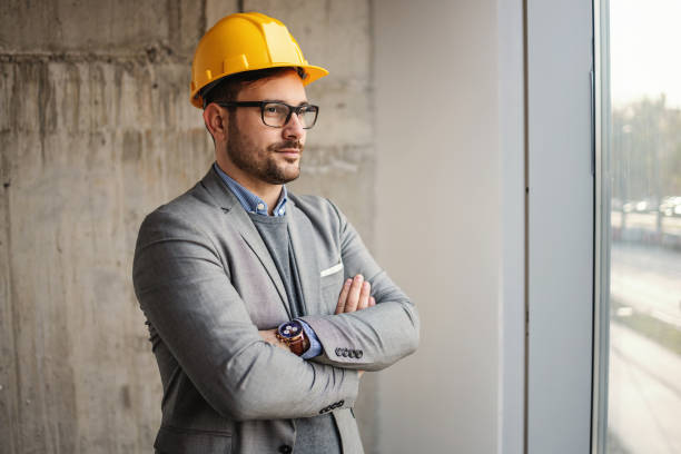 istock Successful architect standing in building in construction process with arms crossed and looking trough window. 1300996111