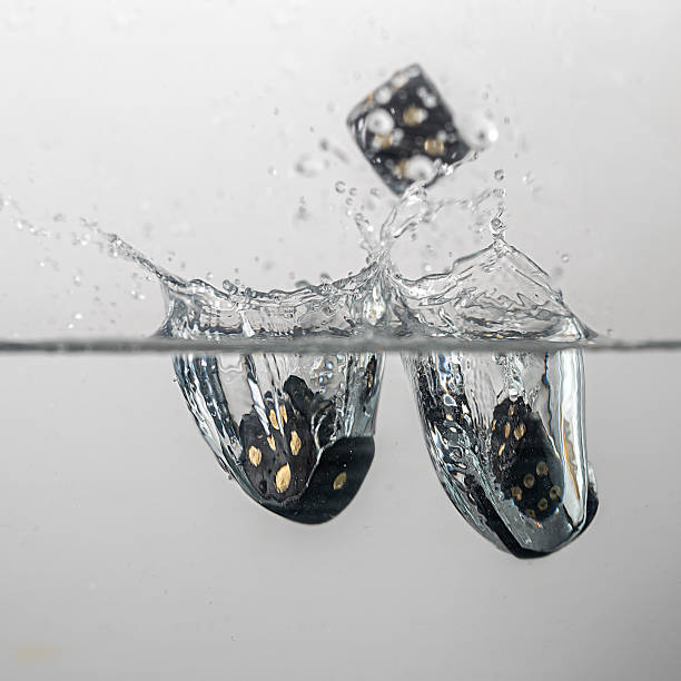 istock Black game cubes fall into the water with splashes 1300996157