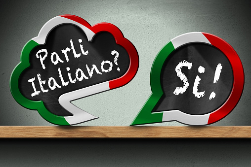 3D illustration of two speech bubbles with Italian flag and question Parli Italiano? and Si! (Do you speak Italian? and Yes!). On a wooden shelf with a wall on background.