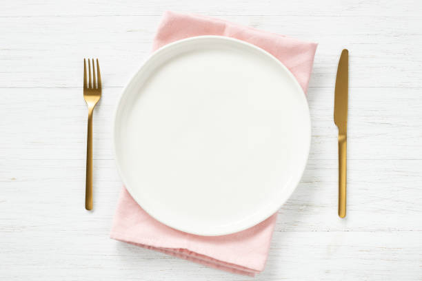 istock White empty plate and golden cutlery on wooden table. 1300997550