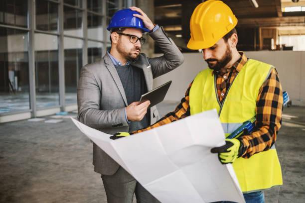 istock Supervisor getting upset about works. Construction site worker holding blue prints and looking at it. Something got wrong. 1300998539
