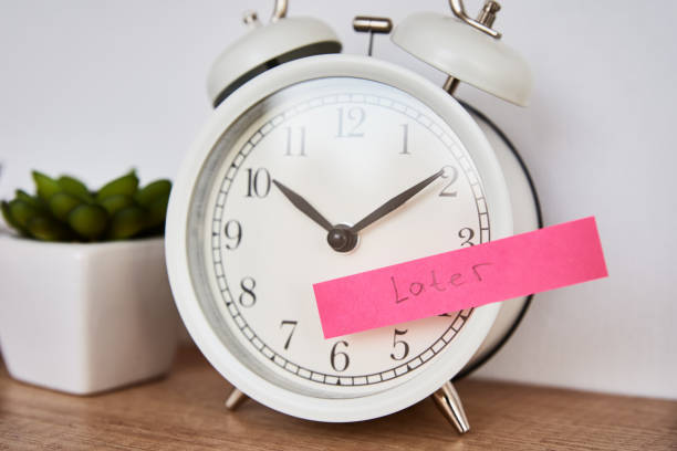 istock Procrastination and delay concept. Sticky note with word later on white alarm clock. Urgency time 1301000224
