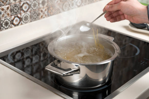 調理鍋に塩のスプーンを追加する男性の手 - salty water ストックフォトと画像
