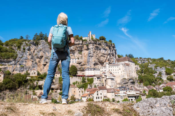 Female tourist at viewpoint looking across the valley to the village of Rocamadour in the Dordogne region of France.