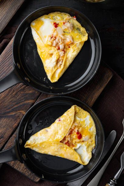 istock Thai  Asian omelette, fresh red chilli, brown and white crabmeat, lemon, Cheddar cheese, eggs, on frying iron pan, on dark wooden background, top view flat lay 1301004054