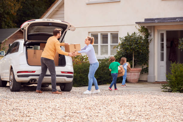 Family Outside New Home On Moving Day Loading Or Unloading Boxes From Car Family Outside New Home On Moving Day Loading Or Unloading Boxes From Car northern europe family car stock pictures, royalty-free photos & images